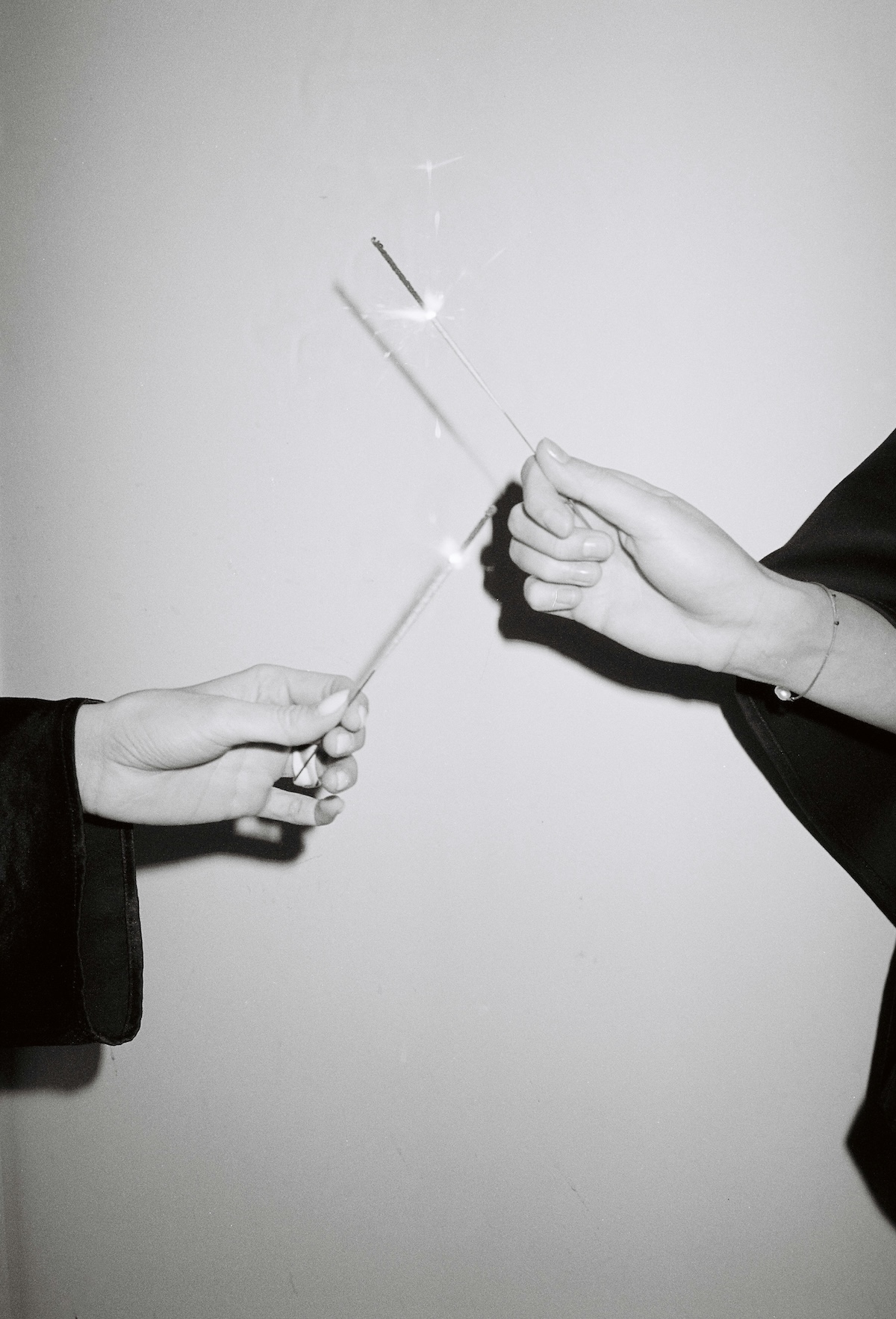 Two people holding sparklers toward each other
